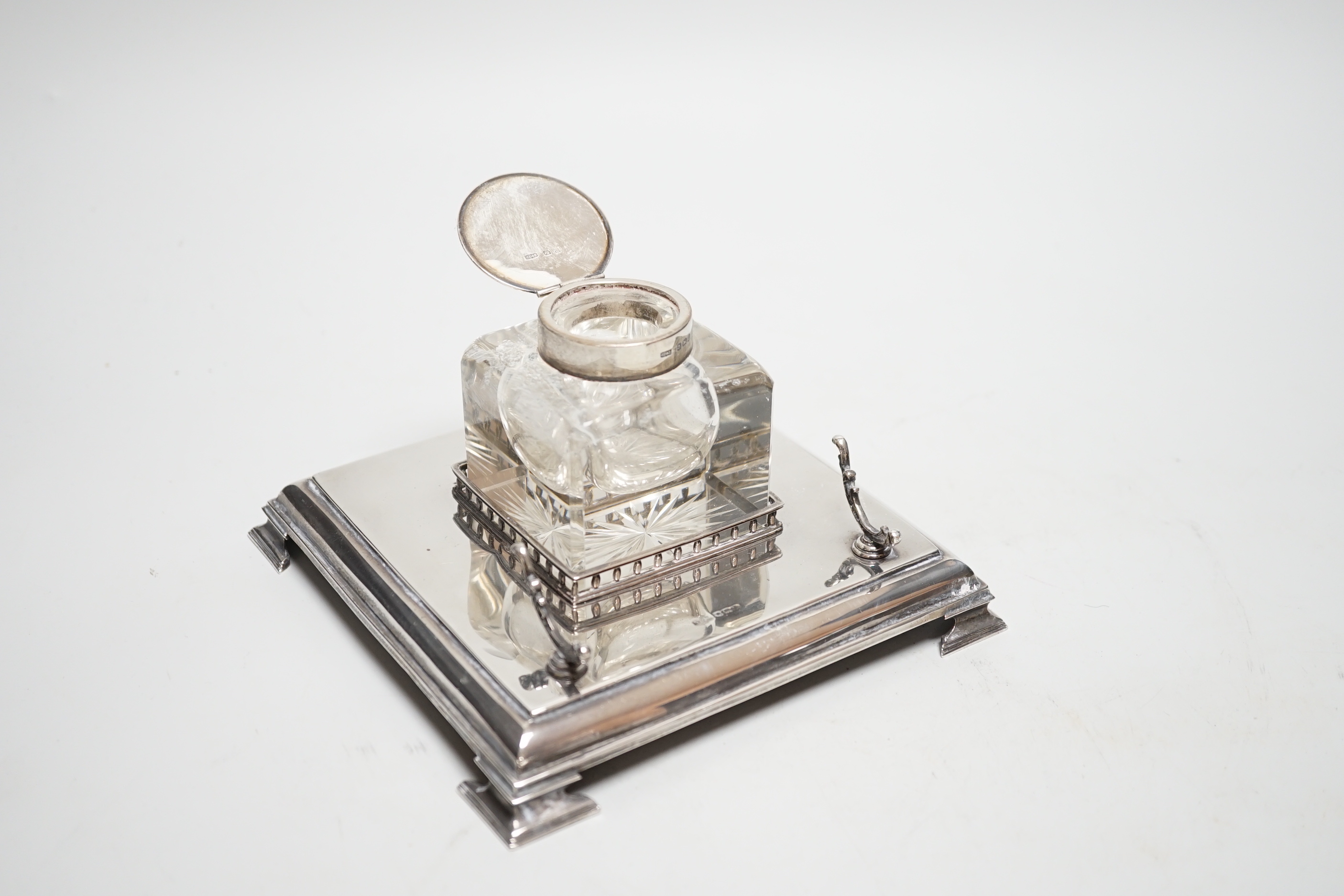 A George V silver inkwell, with mounted glass well and pen rest, James Dixon & Sons, Sheffield, 1928, 15.2cm, base 7.3oz.